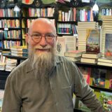 Wolfgang Tänzer steht vor einem Bücherregal in seiner Buchhandlung Bücherwurm.