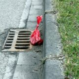 Ein roter Hundekotbeutel liegt an einem Straßenrand