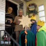 Drei Sternsinger stehen in Herten-Süd vor einer Haustür. Im Eingang steht ein älteres Ehepaar.