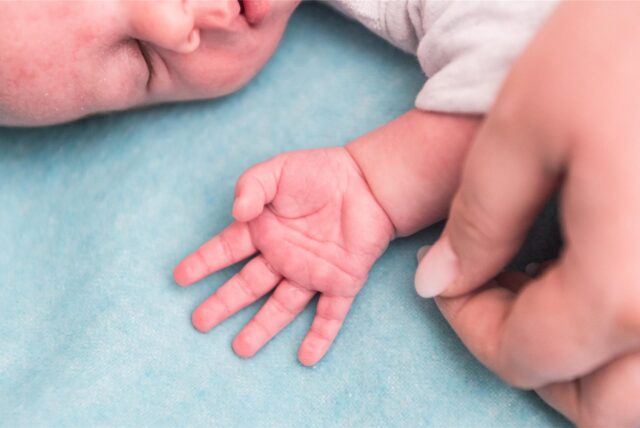Eine Mutter hält die Hand eines wenige Tage alten Kindes.