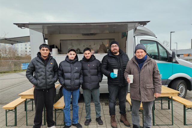 Fünf Männer stehen vor einem Suppenwagen
