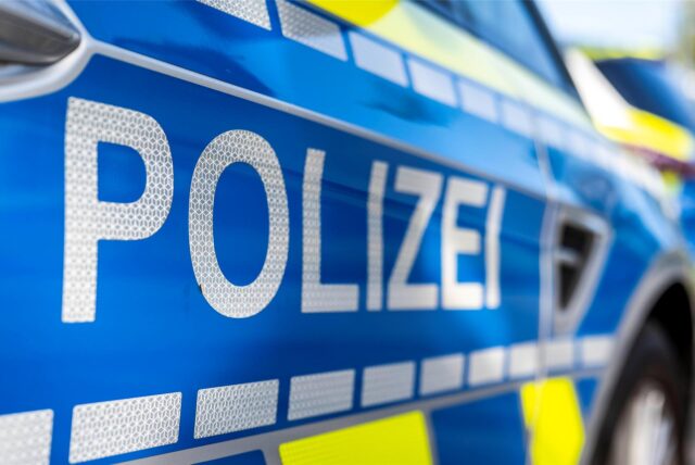 Nahaufnahme eines Streifenwagens. Auf der Beifahrertür ist der Schriftzug „Polizei“ zu lesen.