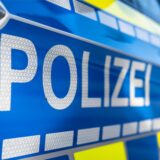 Nahaufnahme eines Streifenwagens. Auf der Beifahrertür ist der Schriftzug „Polizei“ zu lesen.