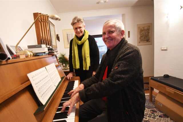 Der Hertener Eugen Spengler sitzt in seinem Musikzimmer am Klavier und spielt ein Stück. Hinter ihm steht seine Ehefrau Bärbel.