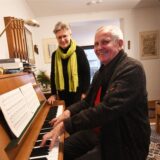 Der Hertener Eugen Spengler sitzt in seinem Musikzimmer am Klavier und spielt ein Stück. Hinter ihm steht seine Ehefrau Bärbel.