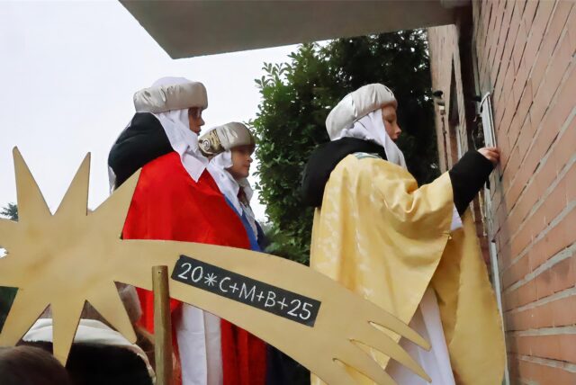 Sternsinger klingeln an einer Tür.