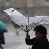 Eine Frau kämpft bei Sturm mit ihrem Regenschirm.