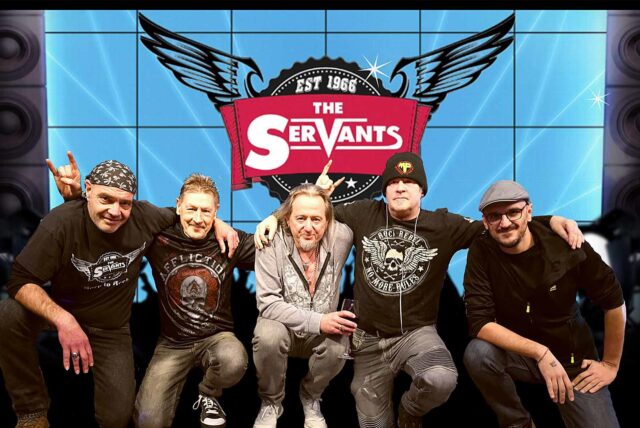 Die fünf Mitglieder der Band The Servants knien vor einer Video-Leinwand, auf der das Band-Logo zu sehen ist.