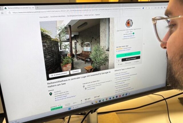 Ein Mann sitzt vor einem PC-Bildschirm und schaut auf eine Immobilienanzeige