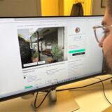 Ein Mann sitzt vor einem PC-Bildschirm und schaut auf eine Immobilienanzeige