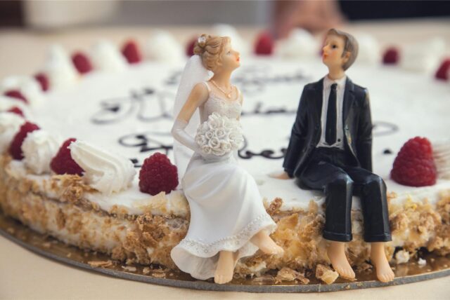 Figuren von einem Brautpaar sind auf einer Hochzeitstorte platziert.