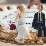 Figuren von einem Brautpaar sind auf einer Hochzeitstorte platziert.