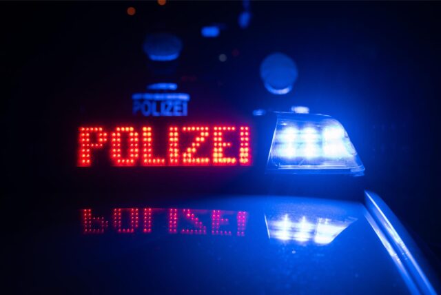 Zwei Polizisten stehen vor einem Polizeifahrzeug