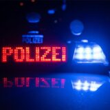 Zwei Polizisten stehen vor einem Polizeifahrzeug