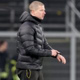 Mike Tullberg zeigt mit dem Finger auf seine Uhr.