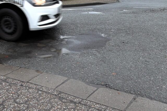 Ein Auto fährt über ein Schlagloch in Datteln.