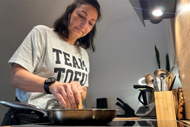 Tatjana Winter raspelt Tofu in eine Pfanne.