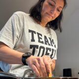 Tatjana Winter raspelt Tofu in eine Pfanne.