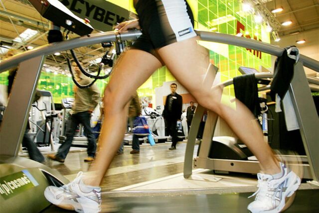 Eine Frau steht auf einem Laufband in einem Fitnessstudio