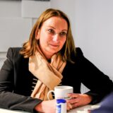 Anja-Christina Rex sitzt in der RZ-Redaktion an einem Tisch, vor sich eine Tasse Kaffee.