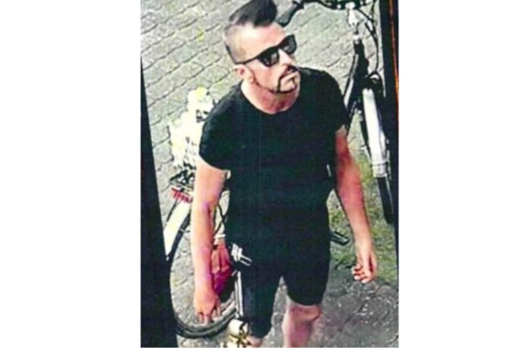 Ein Mann in schwarzer Kleidung und mit Sonnenbrille steht an einem Fahrrad. Ein Mann in schwarzer Kleidung und mit Sonnenbrille steht an einem Fahrrad.