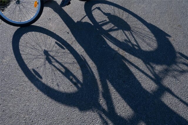 Ein Fahrradfahrer wirft einen Schatten auf die Straße.
