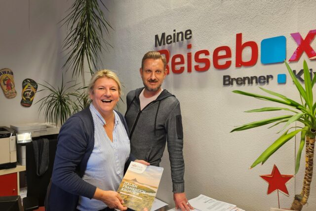 Simone Brenner und Christoph Klix stehen in einem Reisebüro