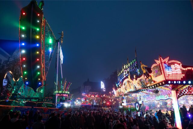 Menschen laufen zwischen Fahrgeschäften über die Allerheiligenkirmes in Soest, eine der größten Kirmessen in NRW.