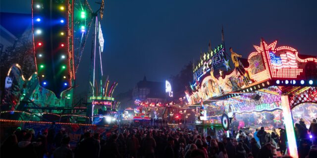 Menschen laufen zwischen Fahrgeschäften über die Allerheiligenkirmes in Soest, eine der größten Kirmessen in NRW.