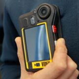 Ein Mitarbeiter der Blankenburger Firma Netco Professional Services GmbH prüft eine Bodycam. Daneben der Arbeitsdirektor des Klinikums Dortmund: Michael Kötzing.