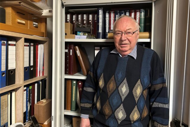 Volker Ruckh steht in seinem Arbeitszimmer in Datteln vor einem Schrank mit vielen Steckbüchern voller Briefmarken.