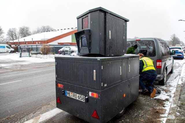 Ein dunkelgrauer Panzerblitzer der Stadt Herten wird als Anhänger an einen Transporter gehängt.