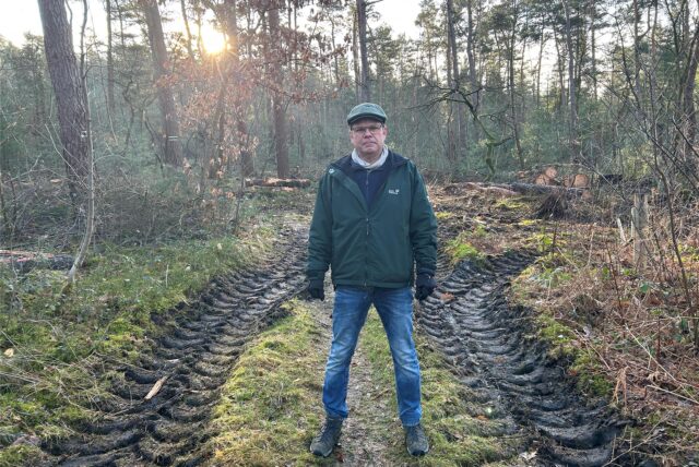 Ein Mann steht auf einem Pfad in der Haard in Datteln. Neben ihm sind die Spuren eines Harvesters im Boden deutlich zu erkennen.