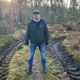 Ein Mann steht auf einem Pfad in der Haard in Datteln. Neben ihm sind die Spuren eines Harvesters im Boden deutlich zu erkennen.