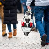 Ein Mann mit einer Einkaufstüte geht durch die Innenstadt.