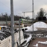 Eine S-Bahn fährt auf dem Weg nach Recklinghausen durch die menschenleere, von Bauzäunen und verschneiten Erdhaufen geprägte Baustelle am künftigen S-Bahnhof Herten-Westerholt.
