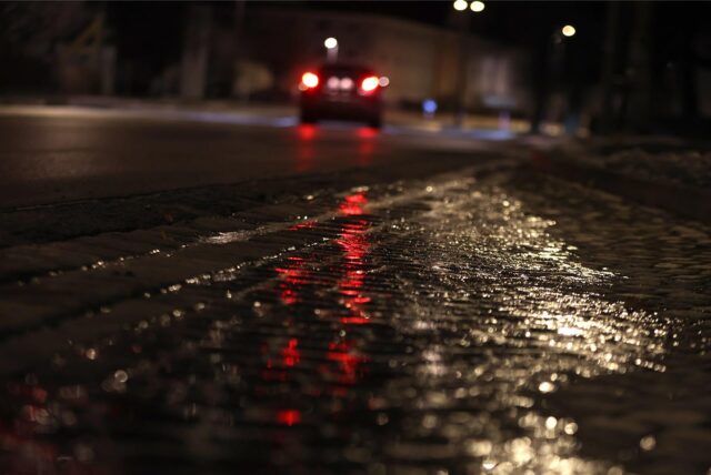 Mit einer dünnen Eisschicht überzogen ist eine Straße am frühen Morgen.