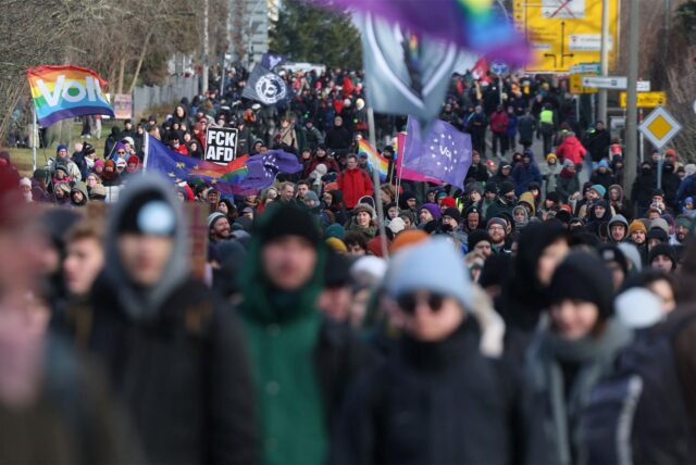 Menschen protestieren gegen den Bundesparteitag der AfD in Riesa mit Flaggen und Plakaten.