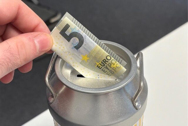 Ein Mann steckt einen Fünf-Euro-Schein in eine Spendendose