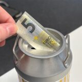 Ein Mann steckt einen Fünf-Euro-Schein in eine Spendendose