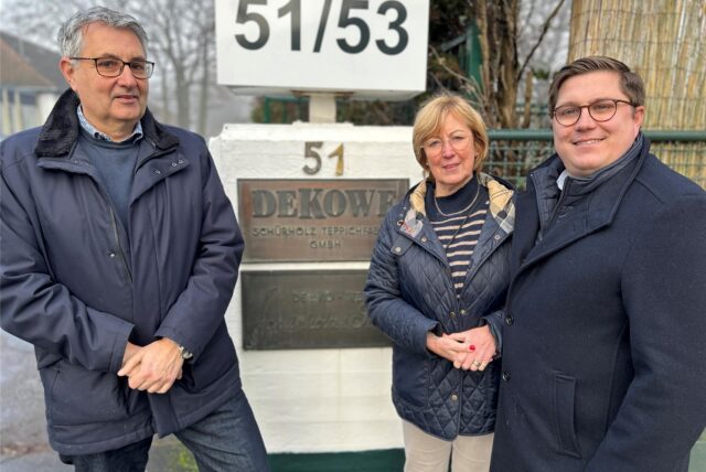 Michael Rohmann, Angelika Schürholz und Hans-Philipp Schürholz stehen vor dem Tor zur Deutschen Kokosweberei (DEKOWE) in Dorsten.