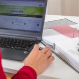 Eine Frau füllt eine Steuererklärung am Laptop aus.