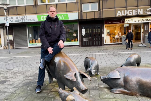 HA-Redakteur Stefan Korte sitzt auf einer der Figuren der Schweineherde in Herten-Mitte.