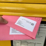 Hand wirft zwei Briefwahlumschläge an das Castrop-Rauxeler Wahlbüro in einen Briefkasten der Deutschen Post.