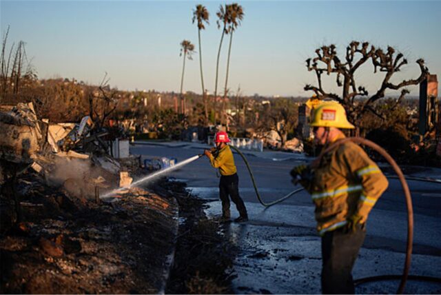 Apple Valley Fire District Captain Manuel Lafarga, Mitte, und Feuerwehrmann James Lyons spritzen heiße Stellen nach dem Palisades Fire im Stadtteil Pacific Palisades von Los Angeles ab.