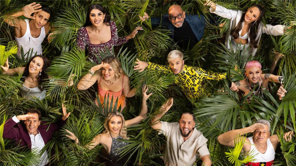Timur Ülker, Yeliz Koc, Pierre Sanoussi-Bliss, Alessia Herren, Lilly Becker, Nina Bott, Sam Dylan, Edith Stehfest, Jörg Dahlmann, Anna-Carina Woitschack, Maurice Dziwak, Jürgen Hingsen, die Kandidaten des Dschungelcamps 2025, posieren zwischen Palmenblättern.