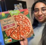 Eine Frau, die eine vegane Pizza hält.