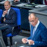 Olaf Scholz schaut zu, während Friedrich Merz im Bundestag eine Rede hält.
