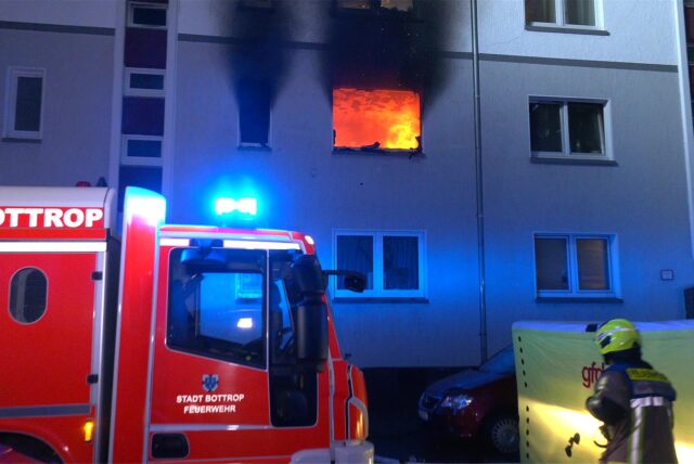 Aus einem Fenster im ersten Stock eines Hauses in Bottrop sind Flammen zu sehen. Die Feuerwehr ist im Einsatz.