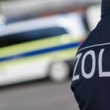 Ein Zollmitarbeiter vor einem Polizeiwagen.